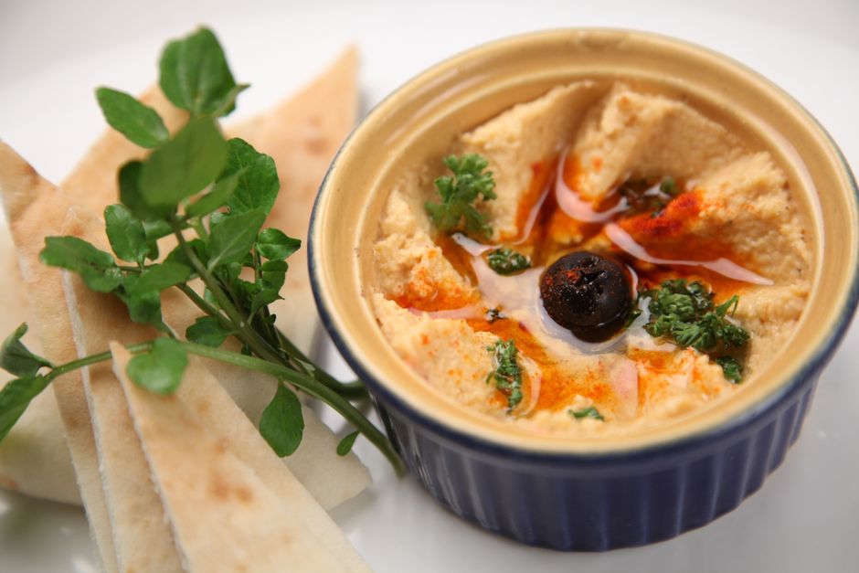Skål med krämig hummus, olivolja och paprika serverad med pitabröd