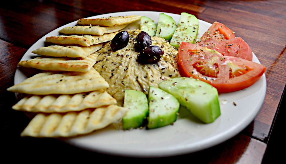 Tallrik med hummus, oliver, pitabröd, gurka och tomat