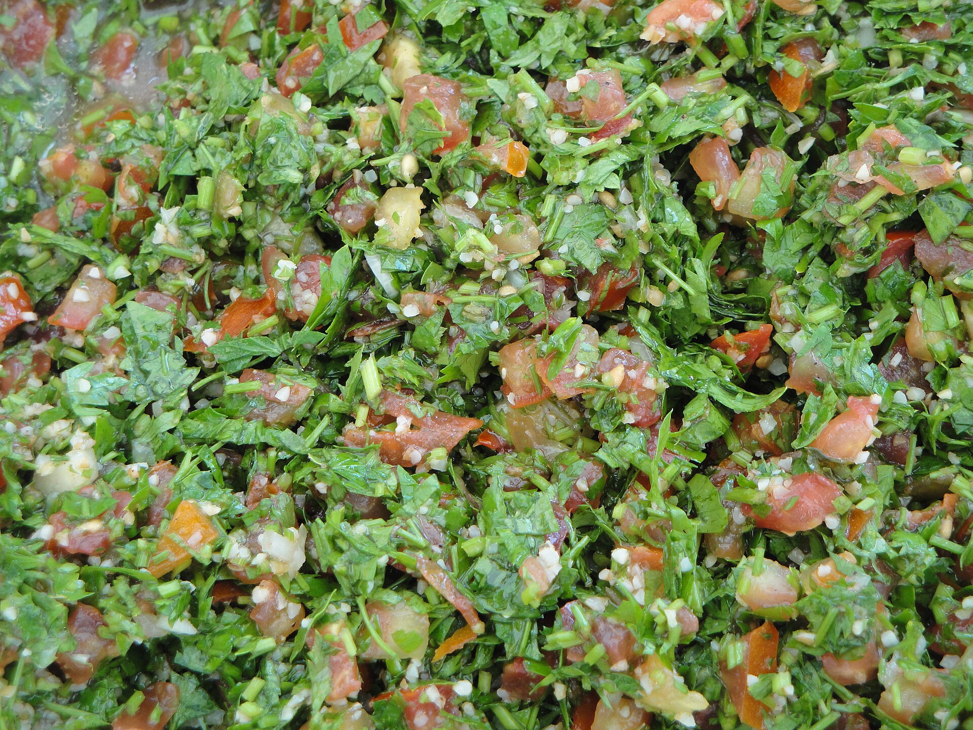 Närbild på tabbouleh med mycket hackad persilja, tomattärningar och några få bulgurkorn