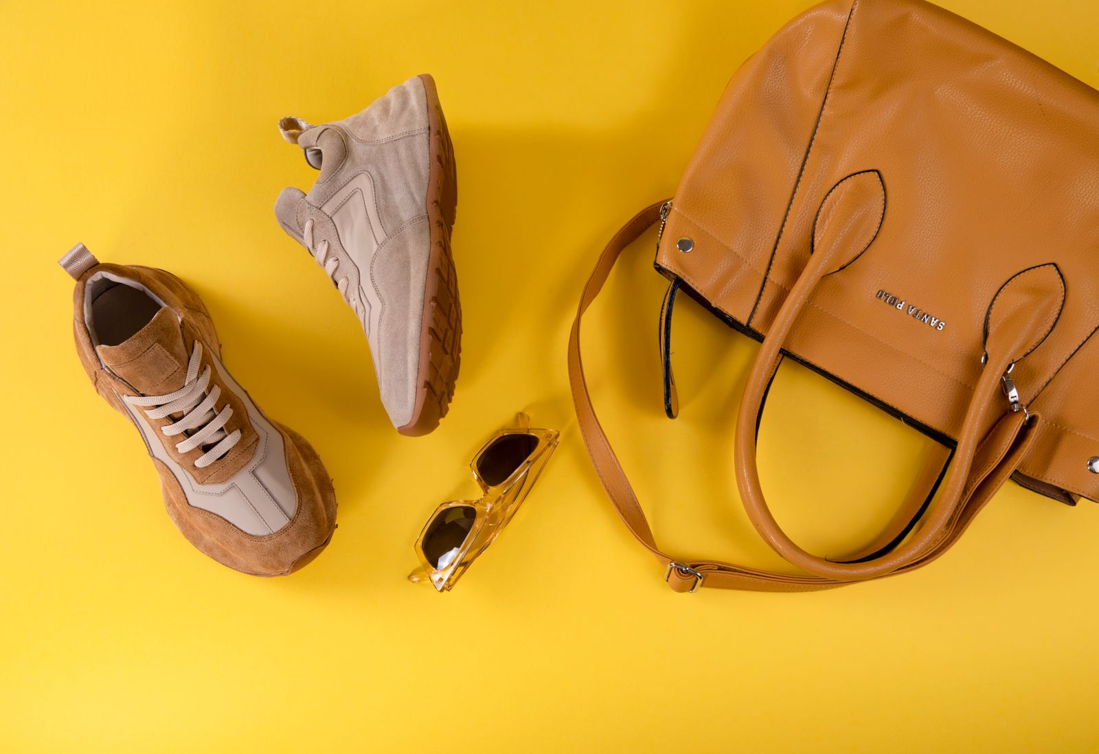 Beige damsneakers stylade med solglasogon och en cognacsfargad vaska