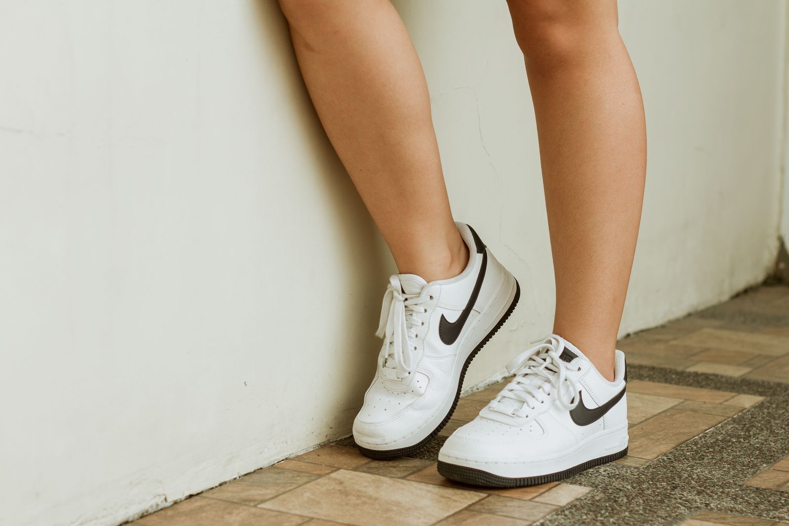Person i vita komfortsneakers lutad mot vägg