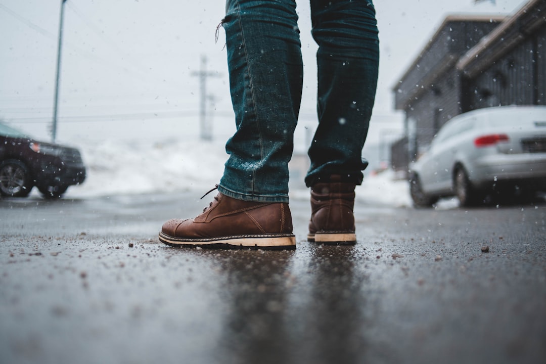 En person i bruna skor på en blöt trottoar med snöslask