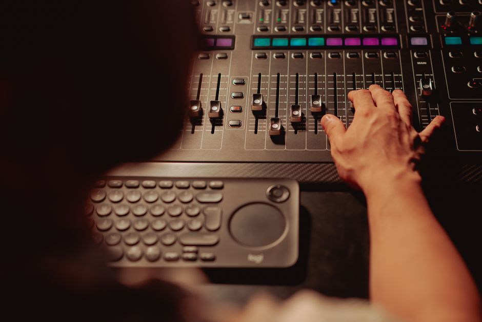 Hands playing a hardware controller connected to a music production setup