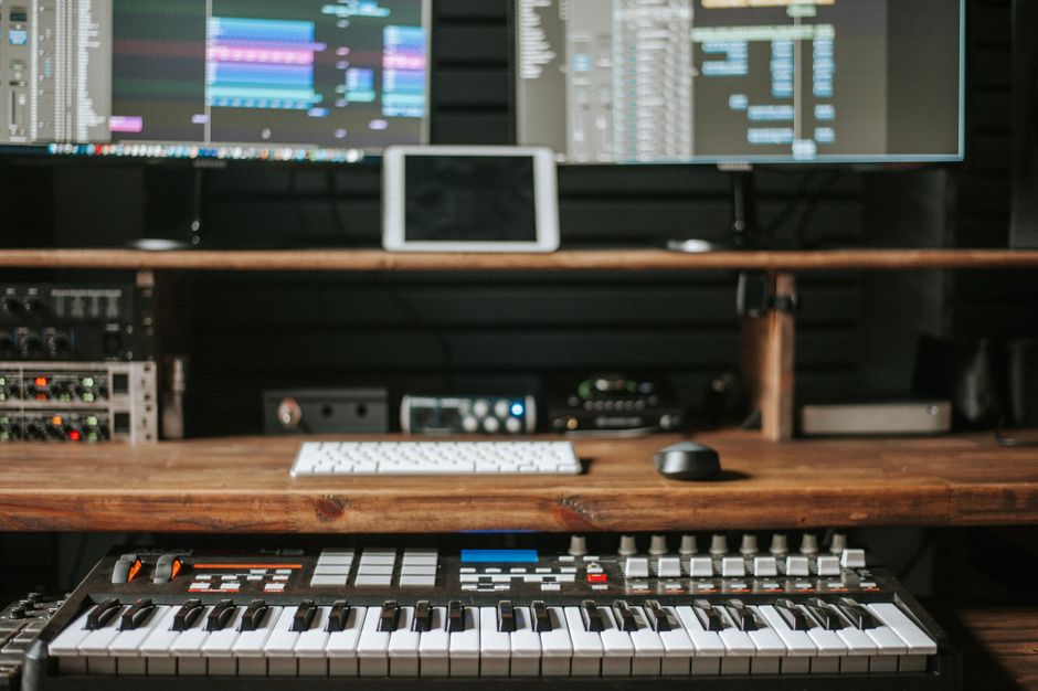 A home studio setup with hardware synthesizers, a keyboard and studio monitors