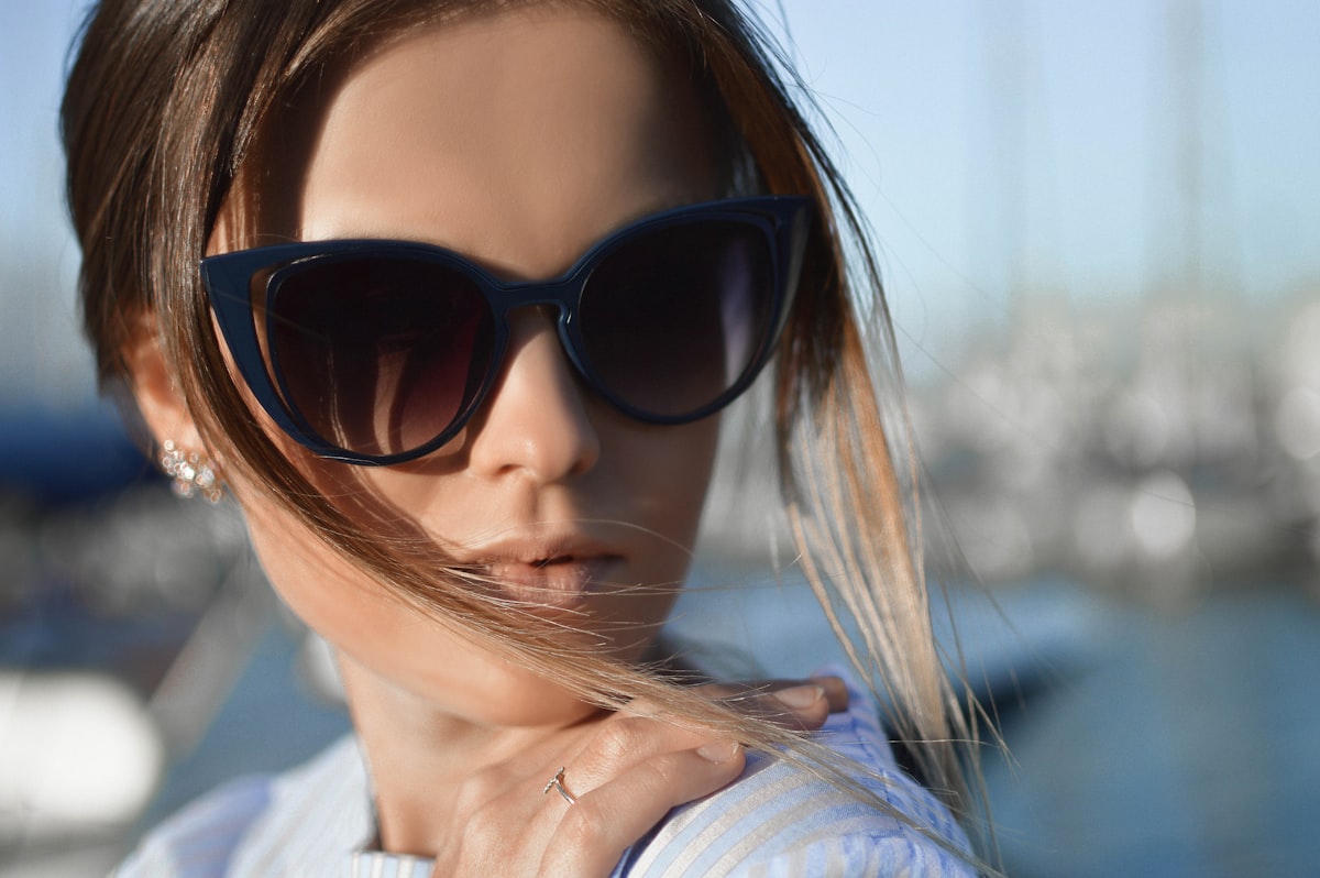 Kvinna med solglasögon i cat-eye-modell i solljus vid en marina
