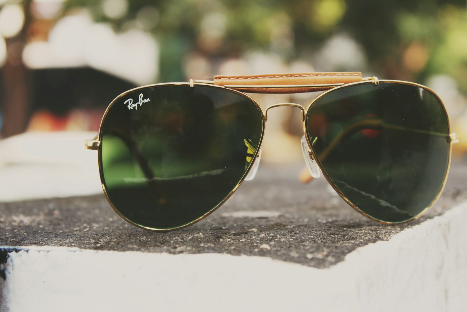 Guldfärgade aviator-solglasögon med droppformade glas på en stenkant