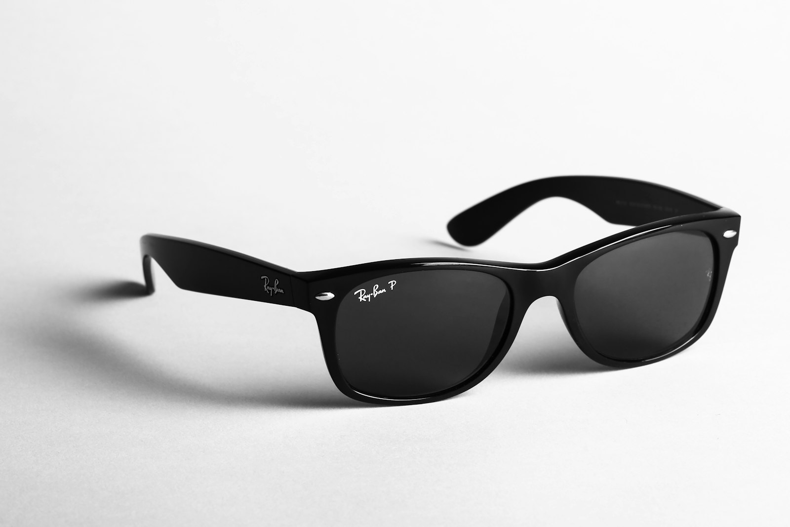 Svarta Ray-Ban Wayfarer-solglasögon i acetat mot ljus bakgrund