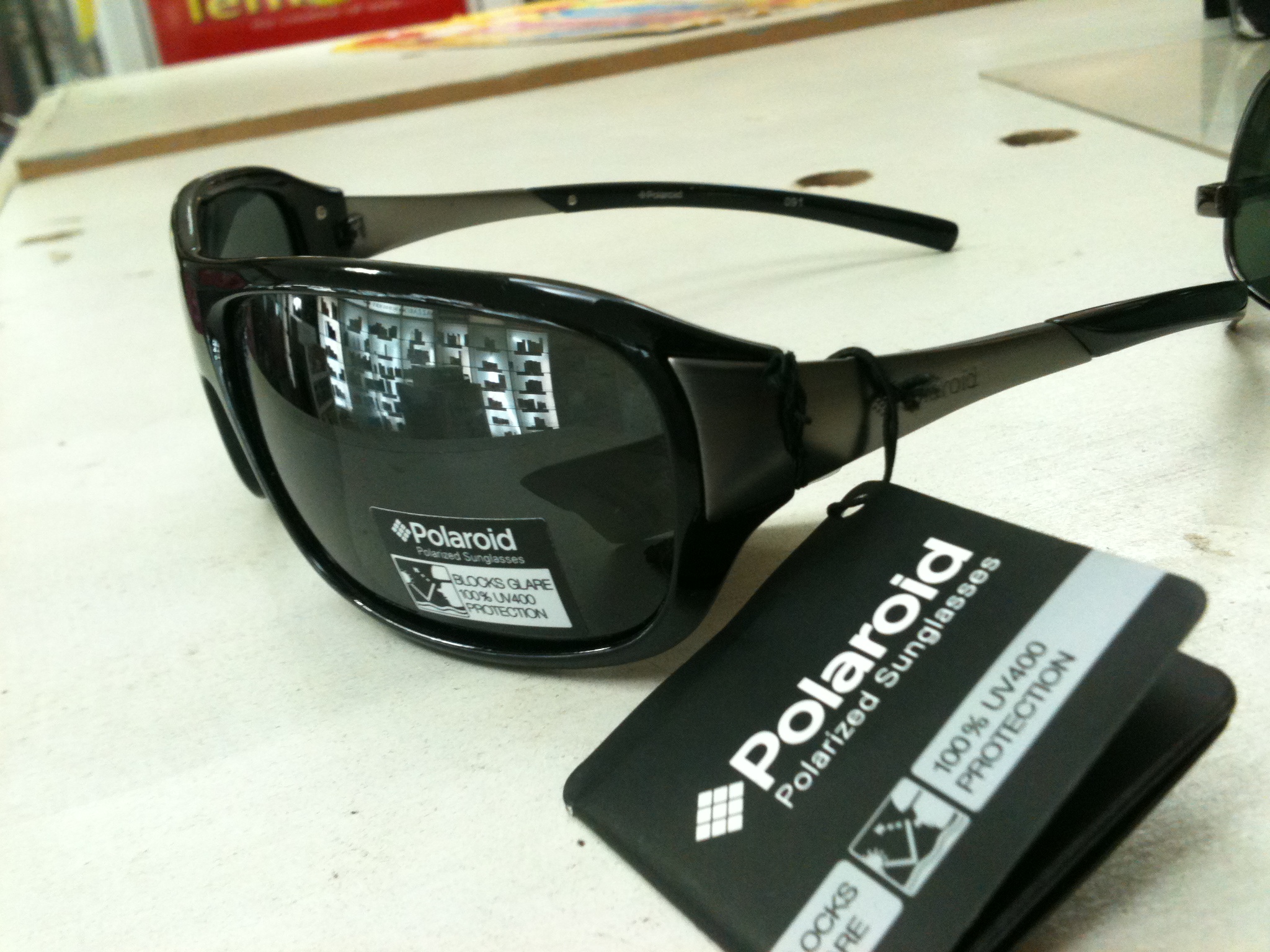Ett par svarta Polaroid-solglasögon med etiketten Polarized Sunglasses och 100% UV400 protection på glaset