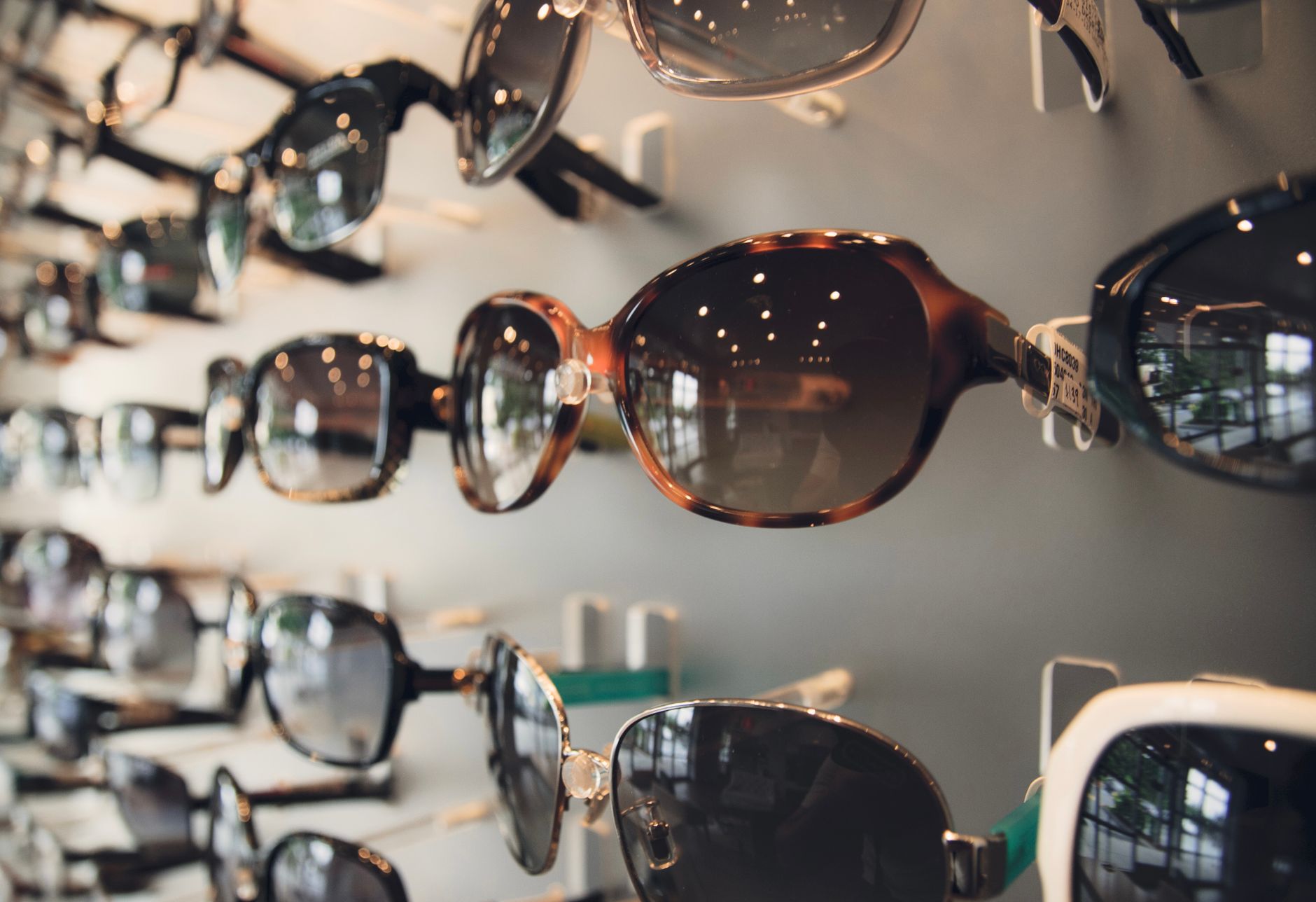 Rader av solglasögon på en vägg i en optikerbutik