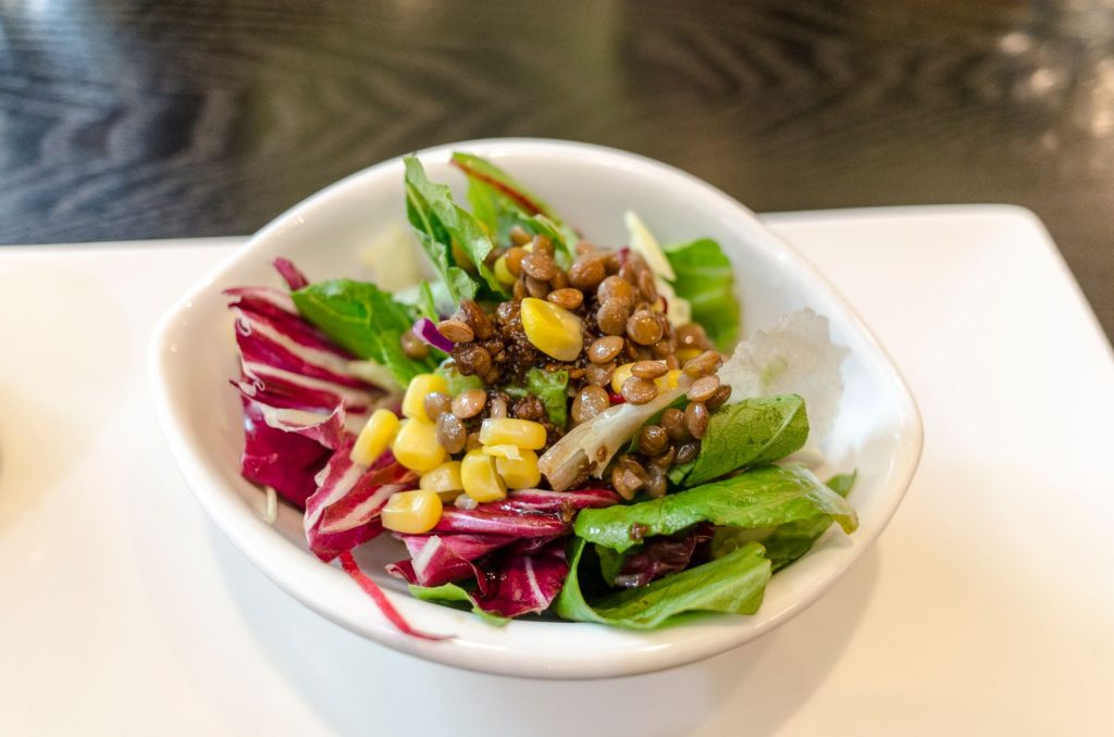 Linssallad med linser, radicchio, majs och gröna salladsblad i en vit skål
