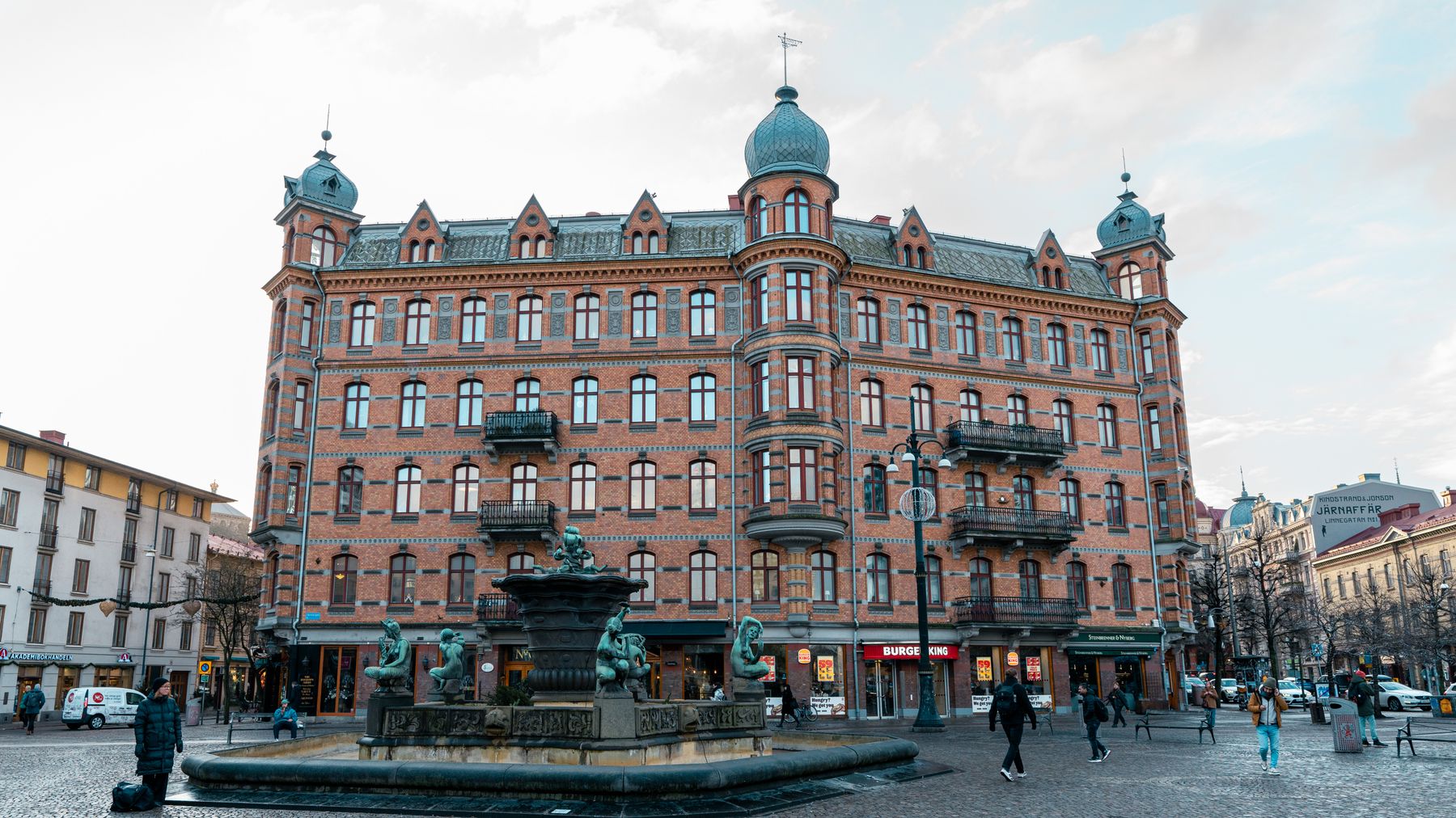 Fontän på ett torg framför tegelhus med torn i centrala Göteborg