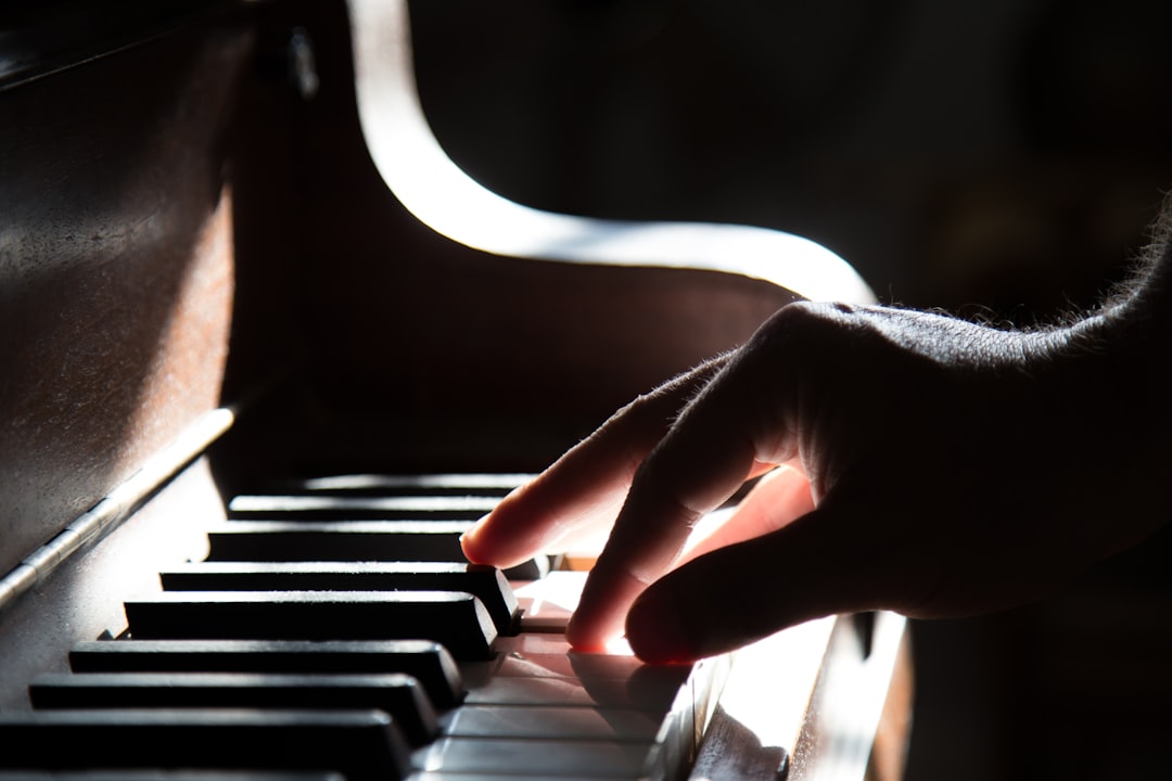 En hand spelar på pianots tangenter i mjukt ljus