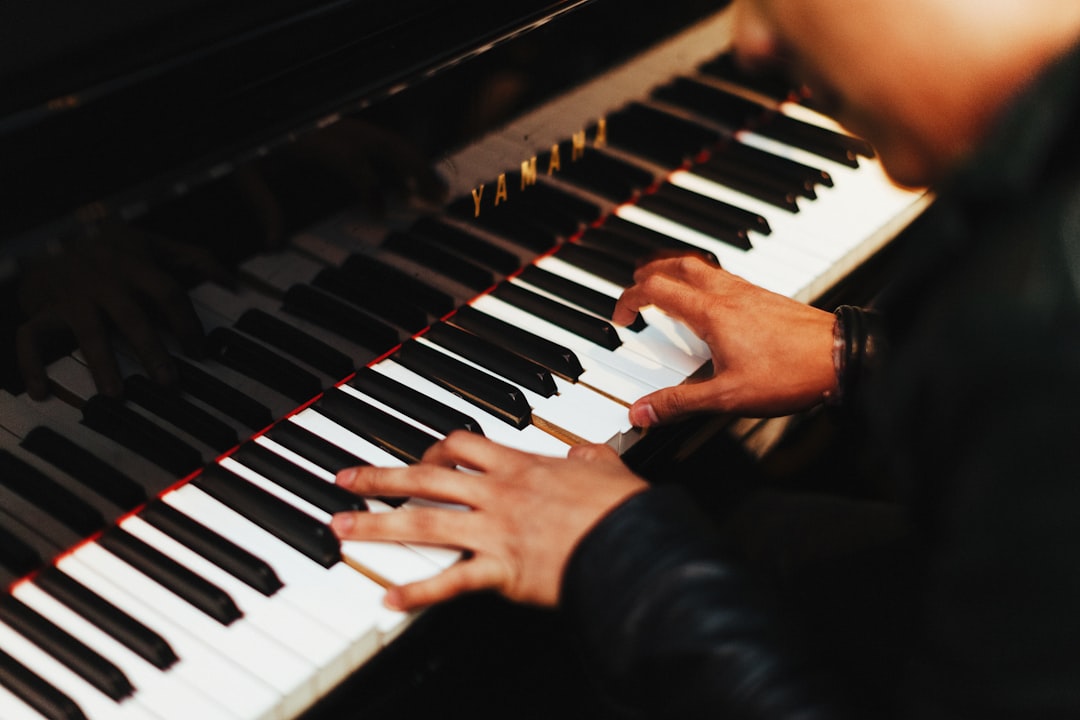 En vuxen persons båda händer spelar på ett svart pianos tangenter