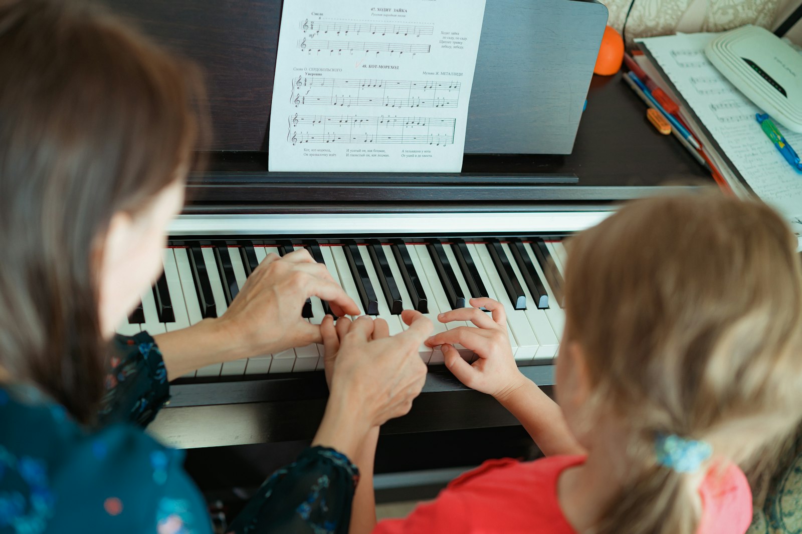 Pianolärare visar ett barn fingersättning på ett digitalpiano