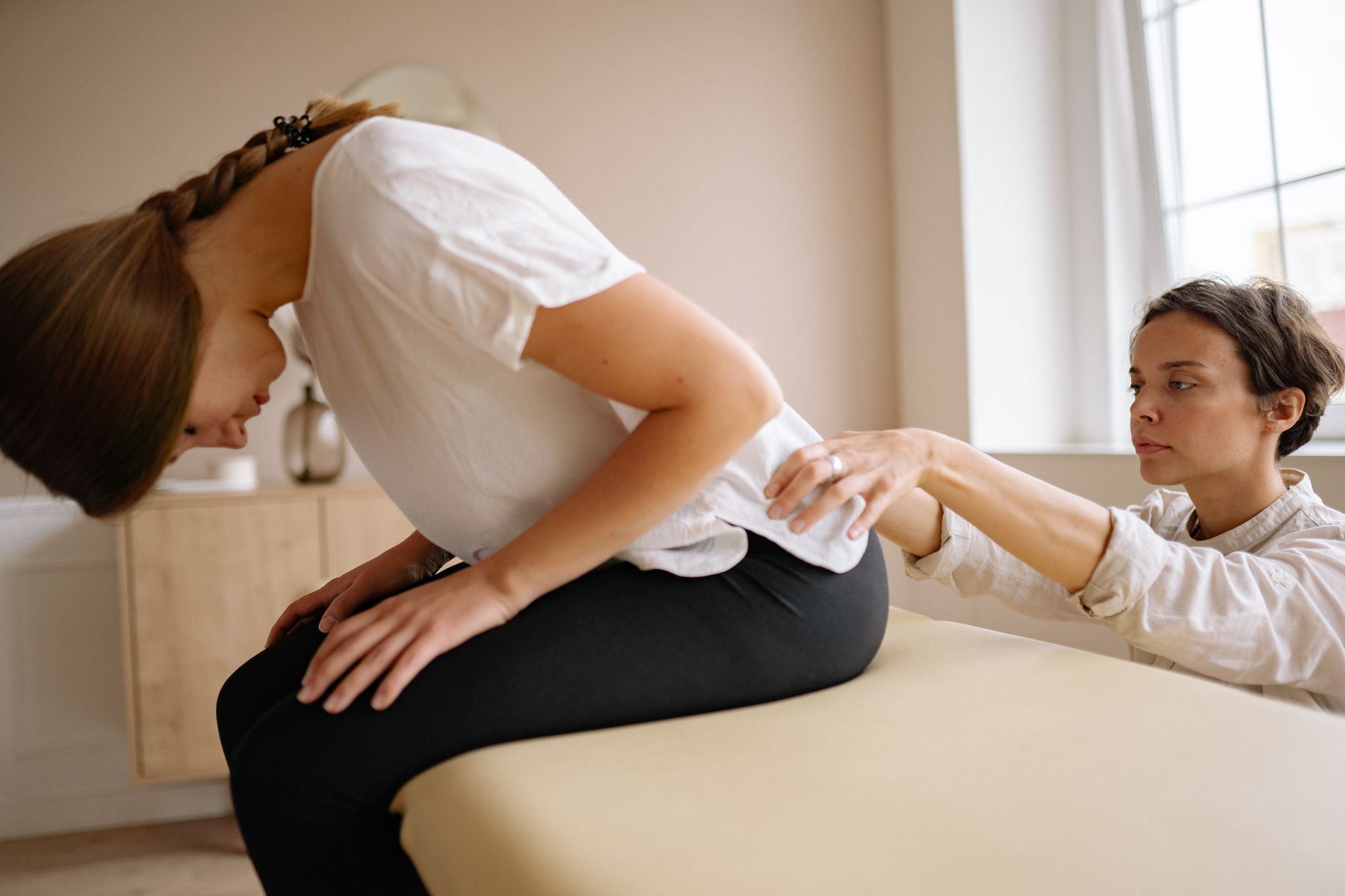 Behandlare undersöker ländryggen på en patient som sitter på en brits