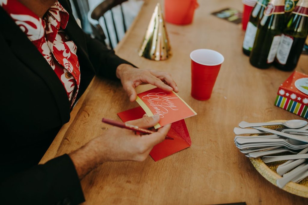 Person skriver en julhälsning vid ett festligt dukat bord