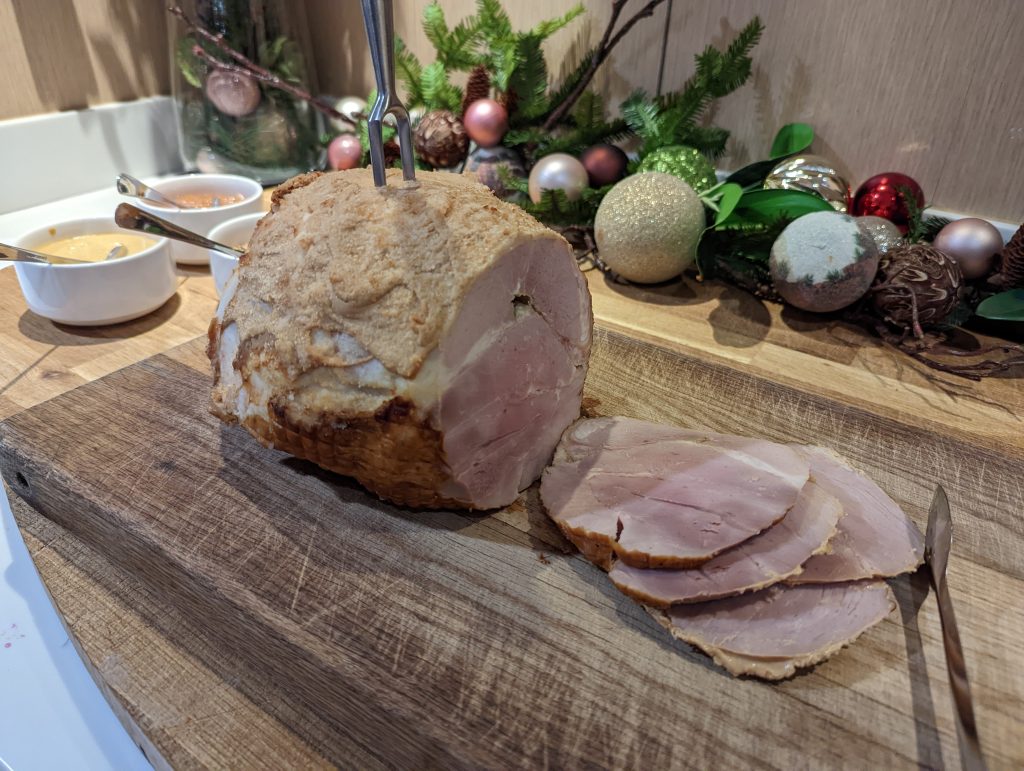 Julskinka i skivor på skärbräda med juldekoration