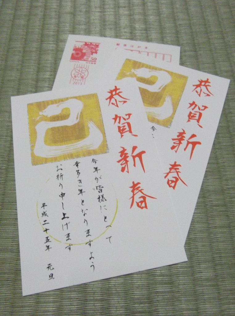 Två japanska nyårskort med ormmotiv och nyårsstämpel på en tatamimatta