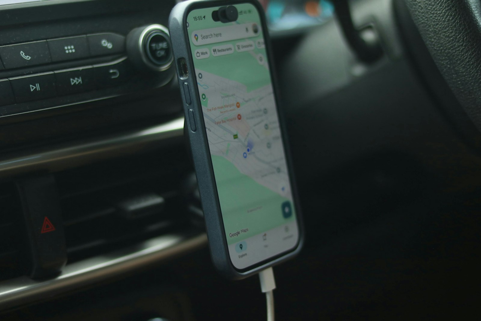 Mobiltelefon i hållare vid bilens mittkonsol, intill knappen för varningsblinkers