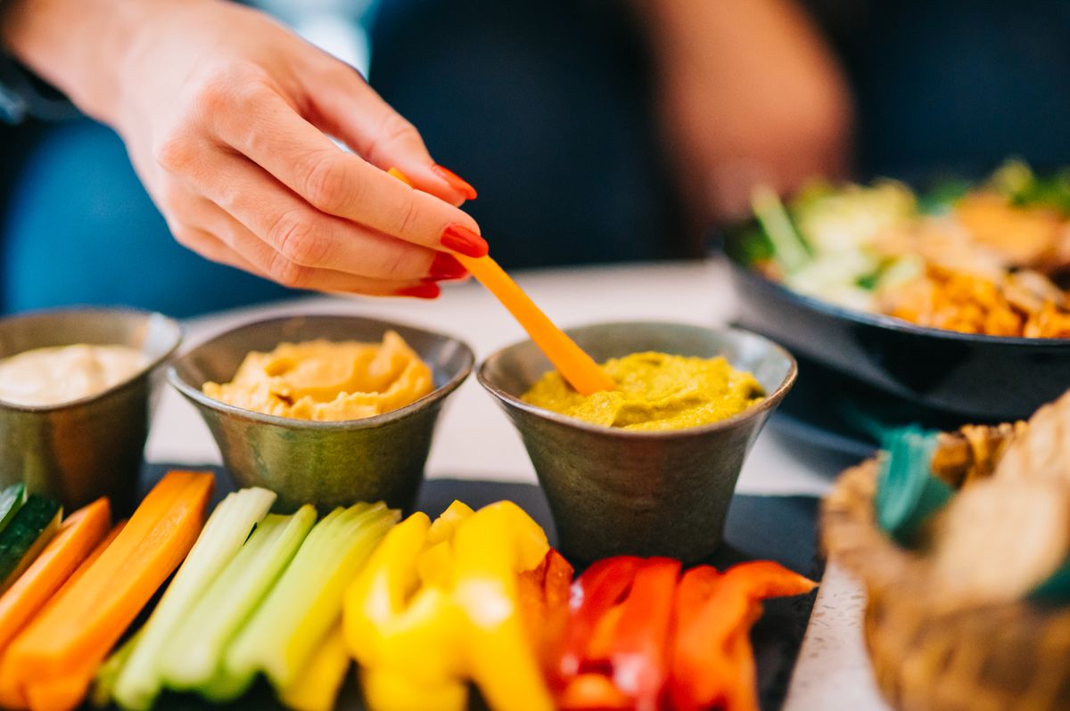 Färgglada grönsaksstavar med veganska dippar på ett vickningsbord