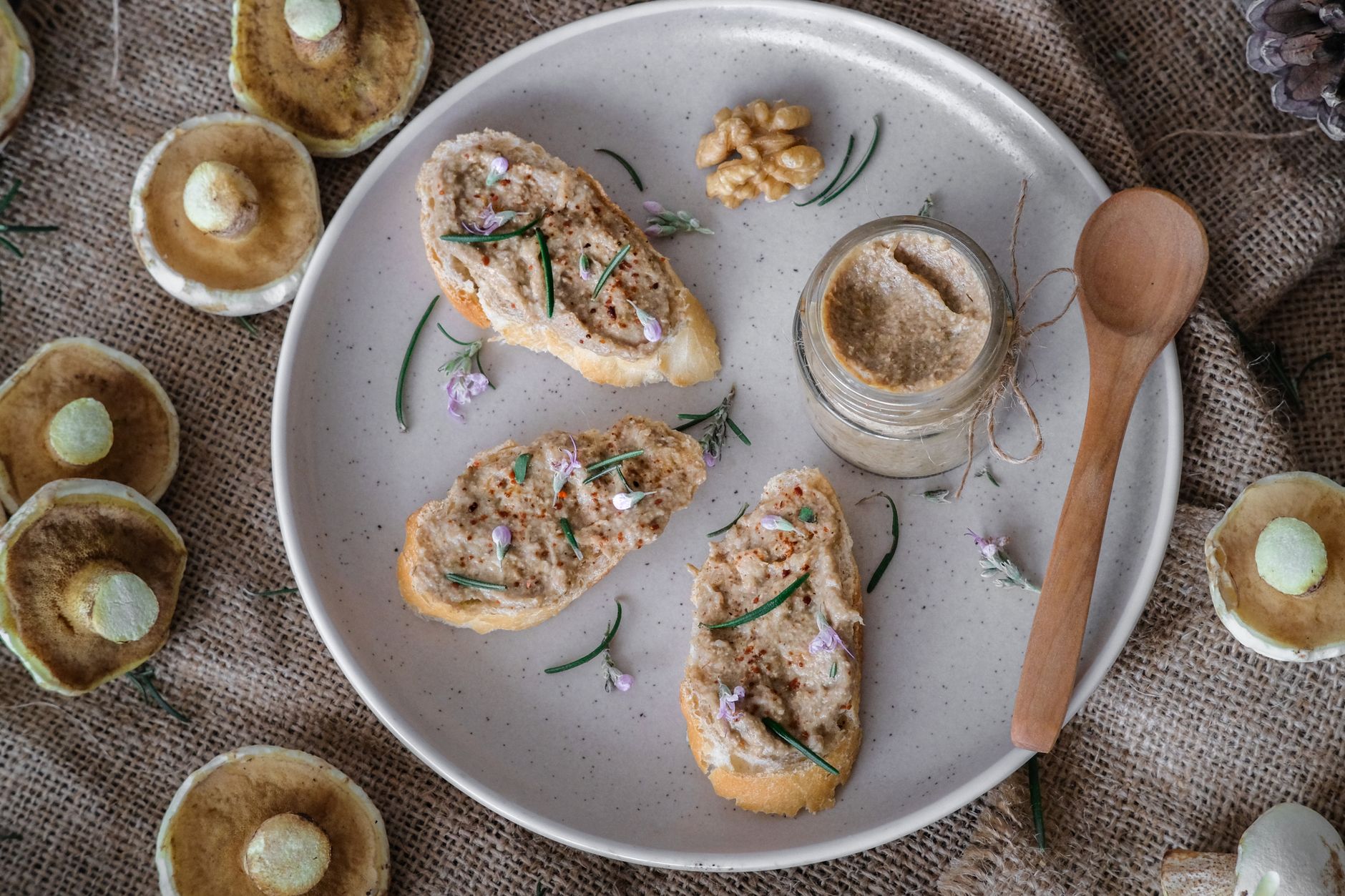 Rostade brödskivor med vegansk pastej på baljväxter och svamp, serverade med en burk pastej och färsk svamp