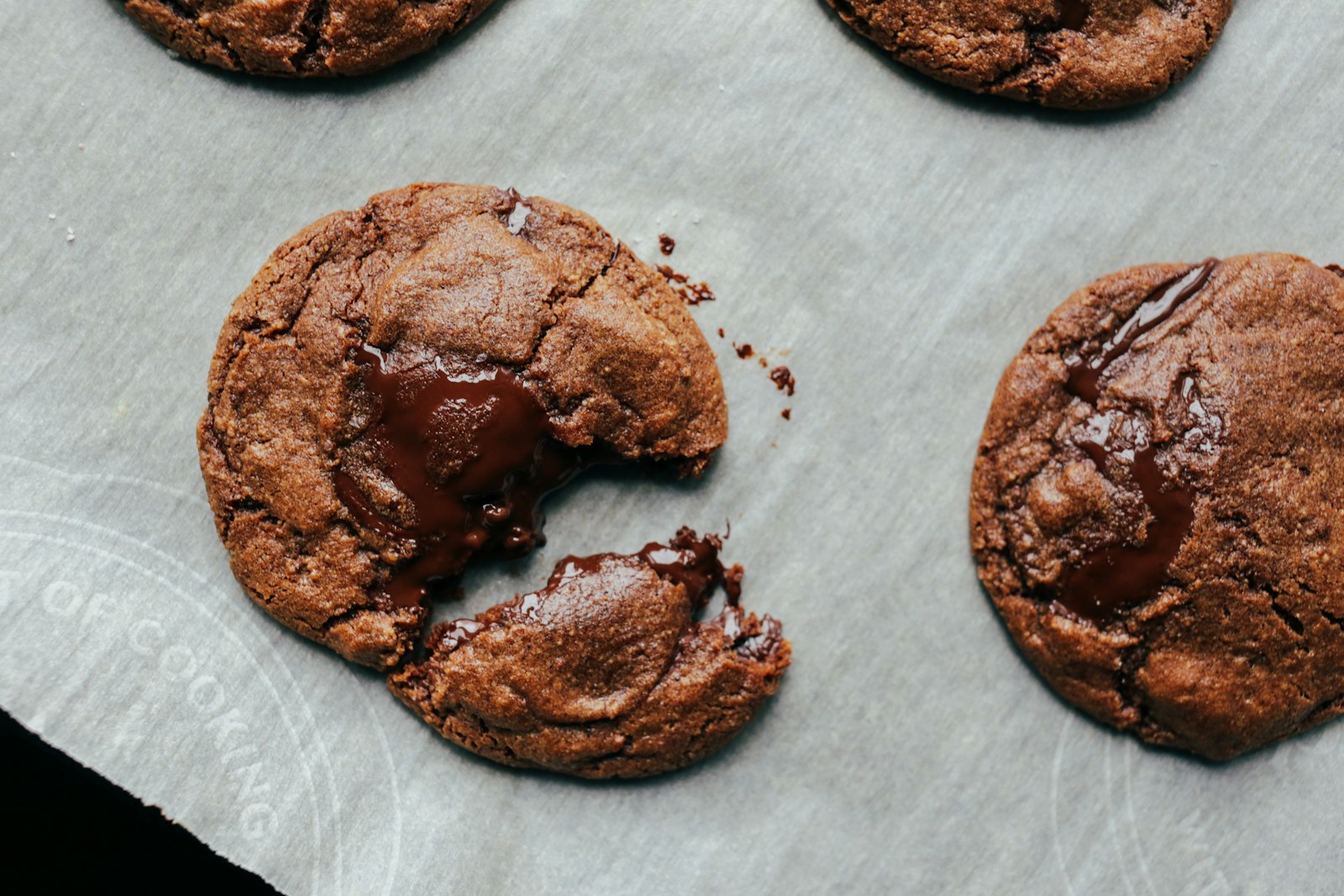 Chokladcookies på bakplåtspapper, en avbruten med smält choklad i mitten