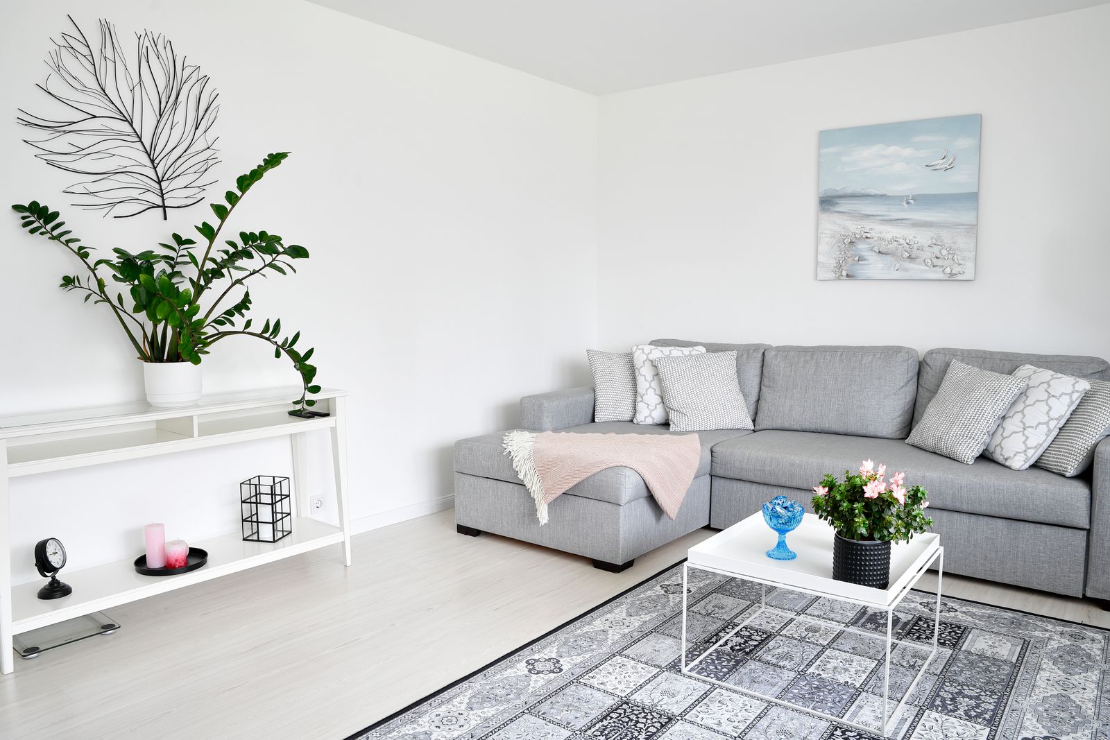 Ljust avskalat vardagsrum med grå soffa stylat inför en bostadsvisning