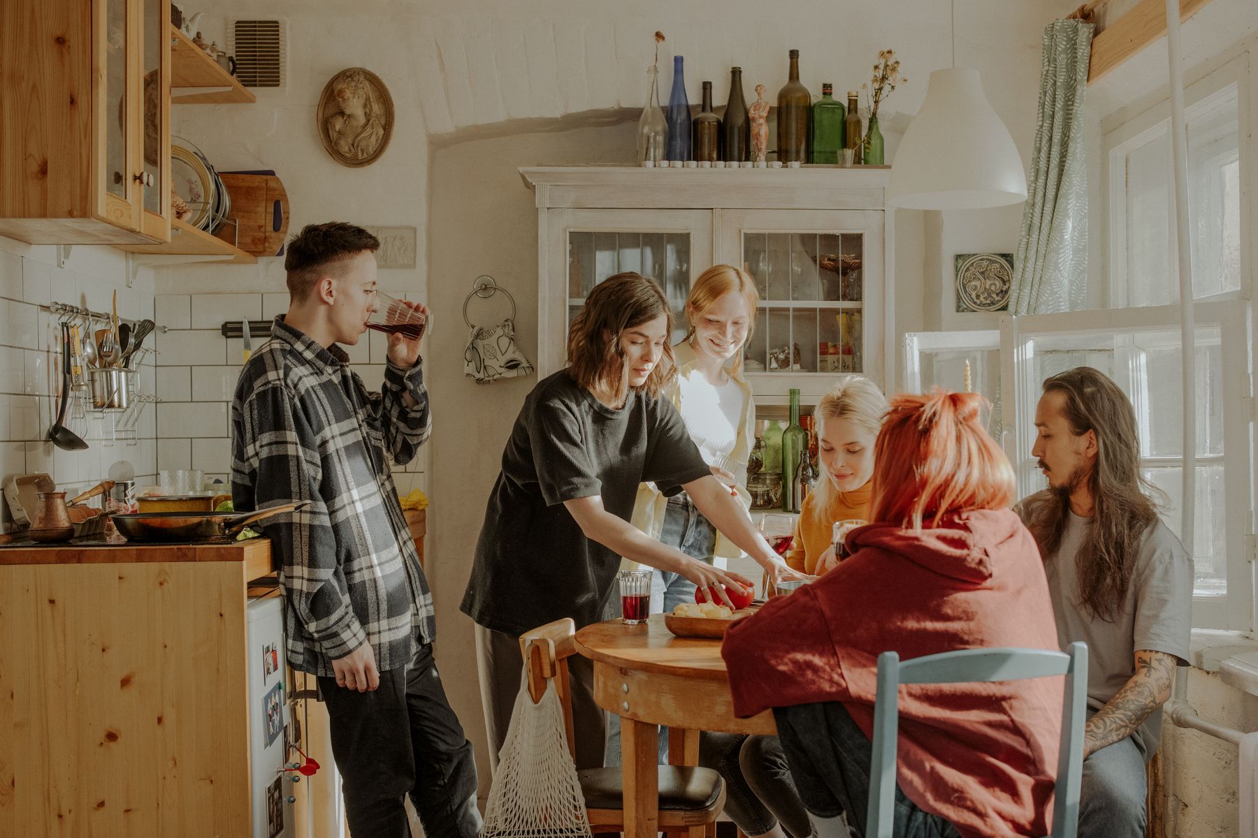 En grupp vänner umgås och lagar mat tillsammans i ett delat kök