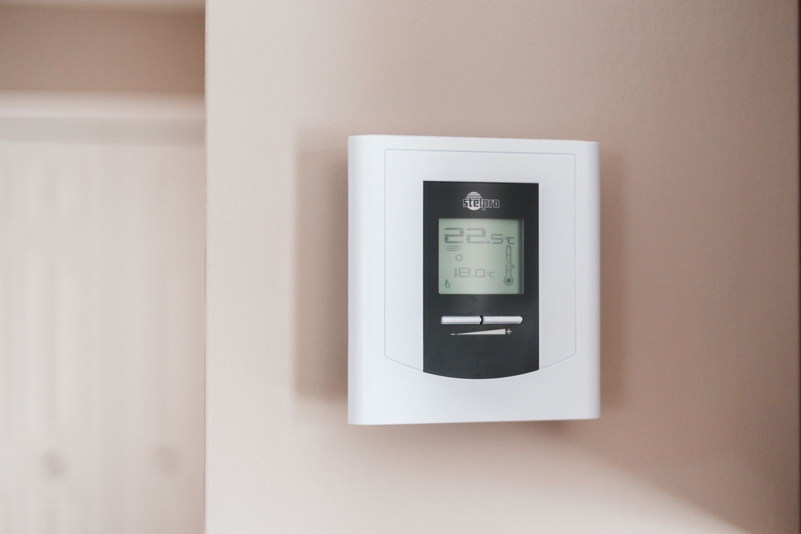 Digital termostat på vägg som visar innetemperatur och önskad temperatur
