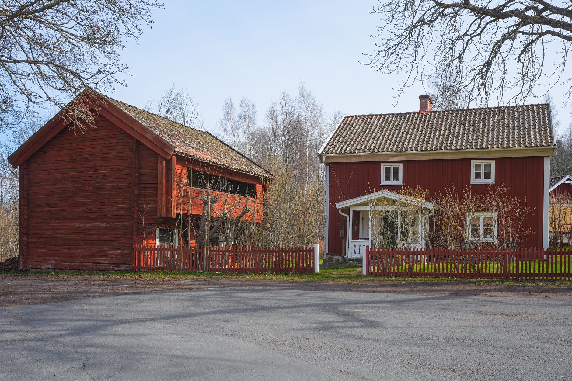 Rött trähus med uthus bakom ett rött staket