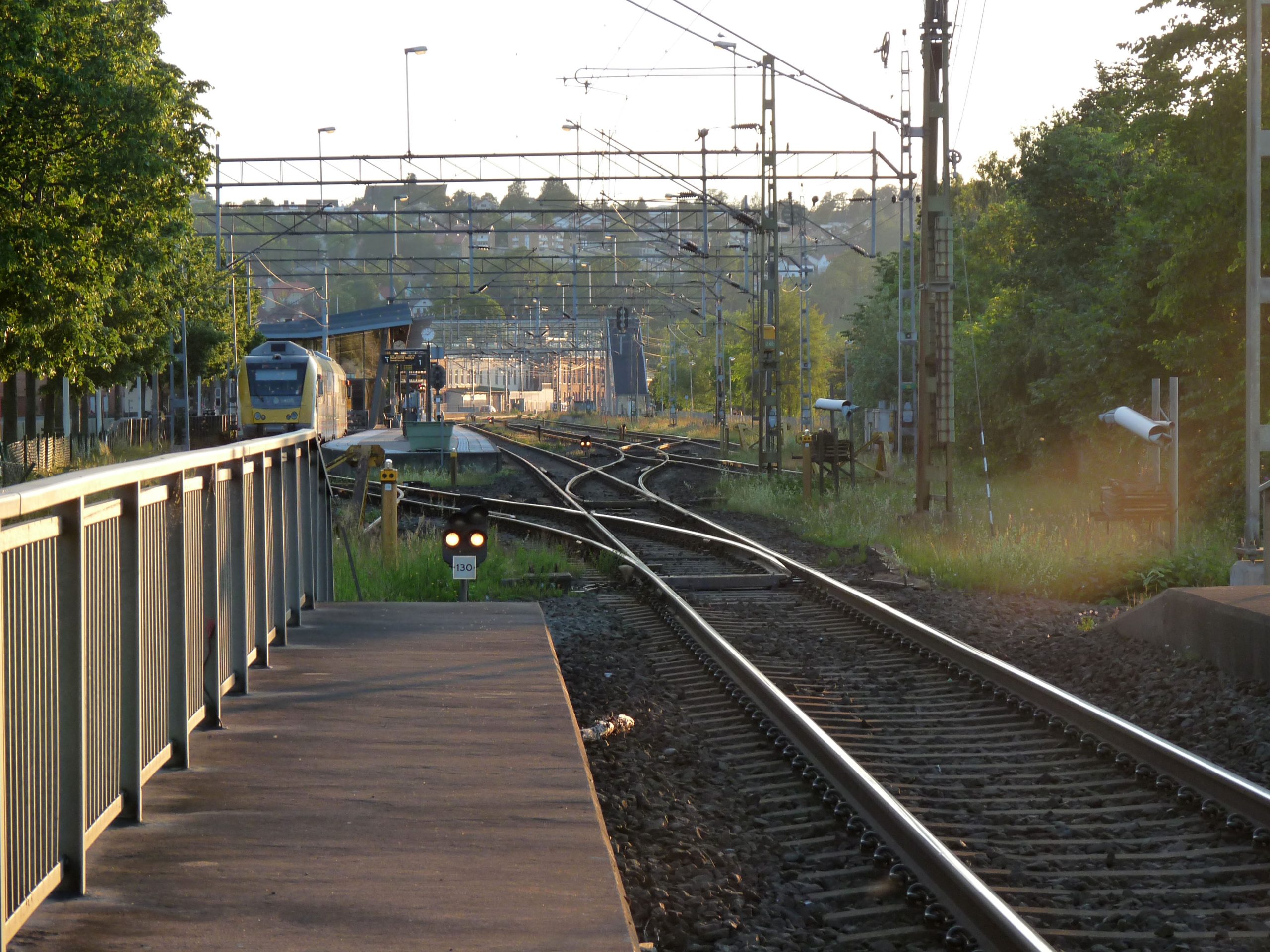 Plattform och spår vid Jönköpings station med ett regionaltåg i kvällsljus