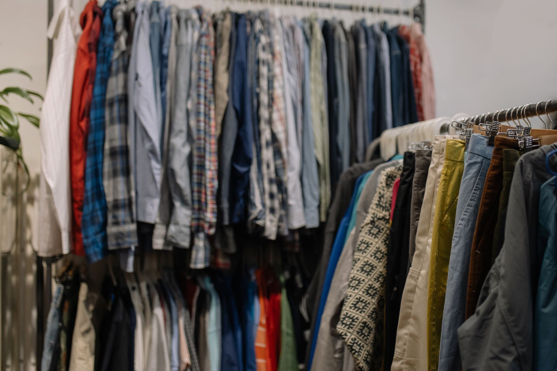 Begagnade skjortor, byxor och jackor på klädstänger i en second hand-butik