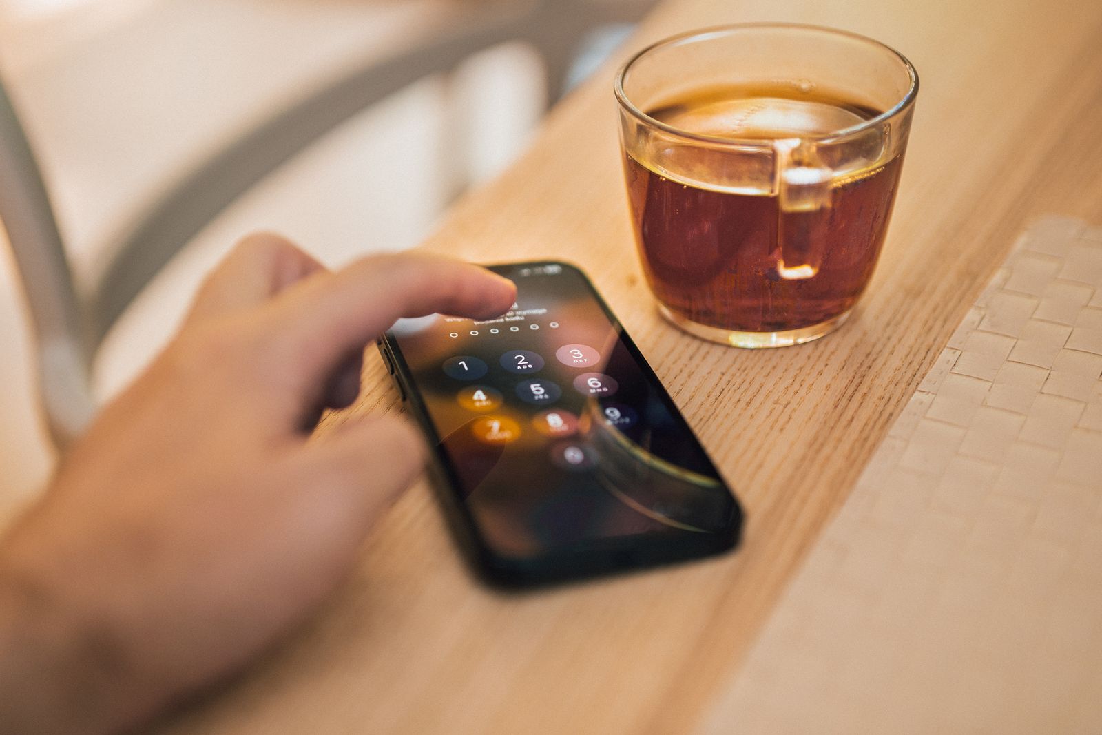 Person knappar in en kod på sin mobiltelefon vid ett kafébord