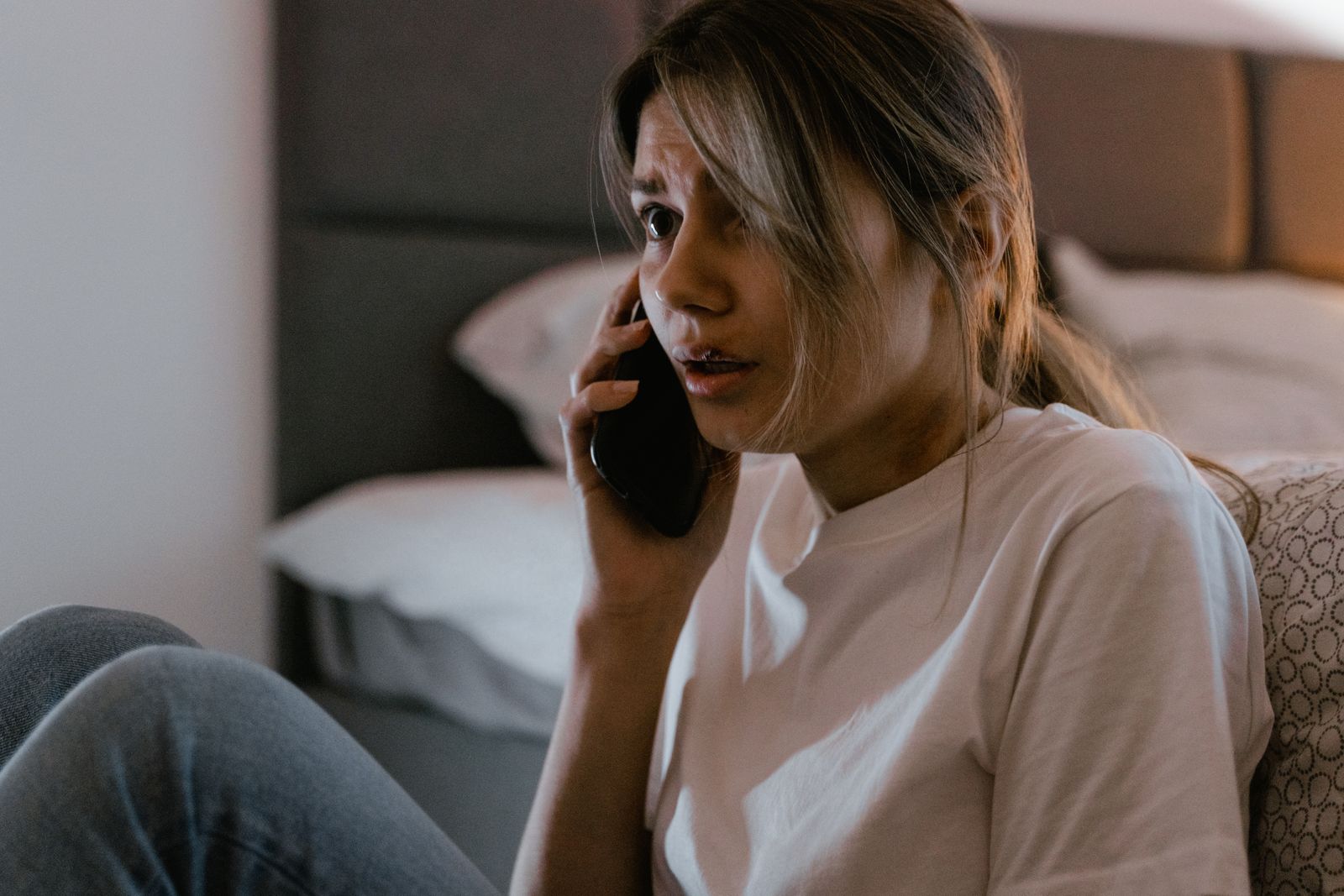 Person sitter med telefonen mot örat och ser bekymrad ut