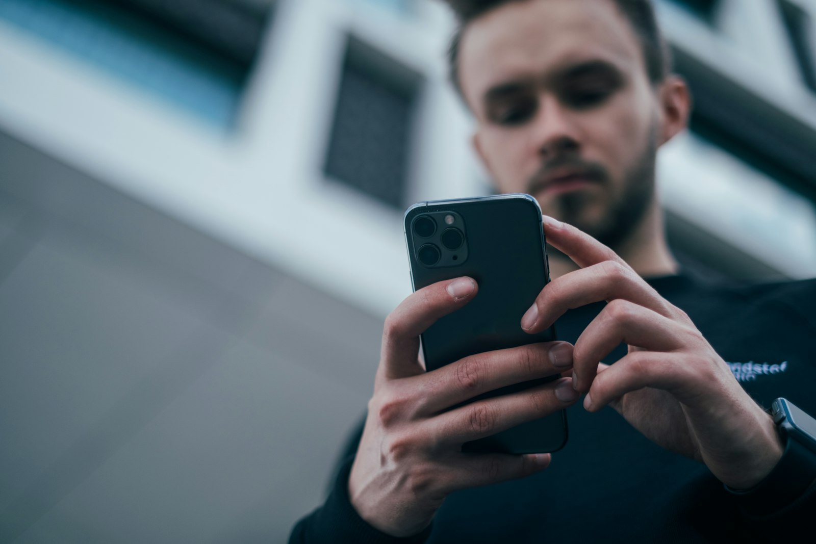 En man tittar ner på sin mobiltelefon som han håller med båda händerna.