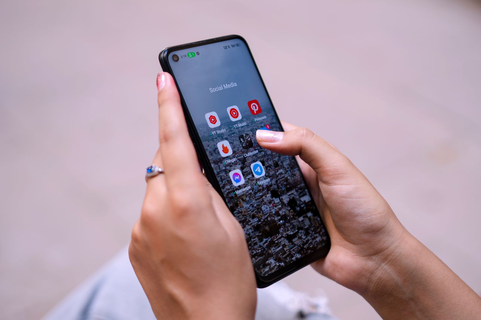 Hand håller en mobil med en mapp av sociala medier-appar