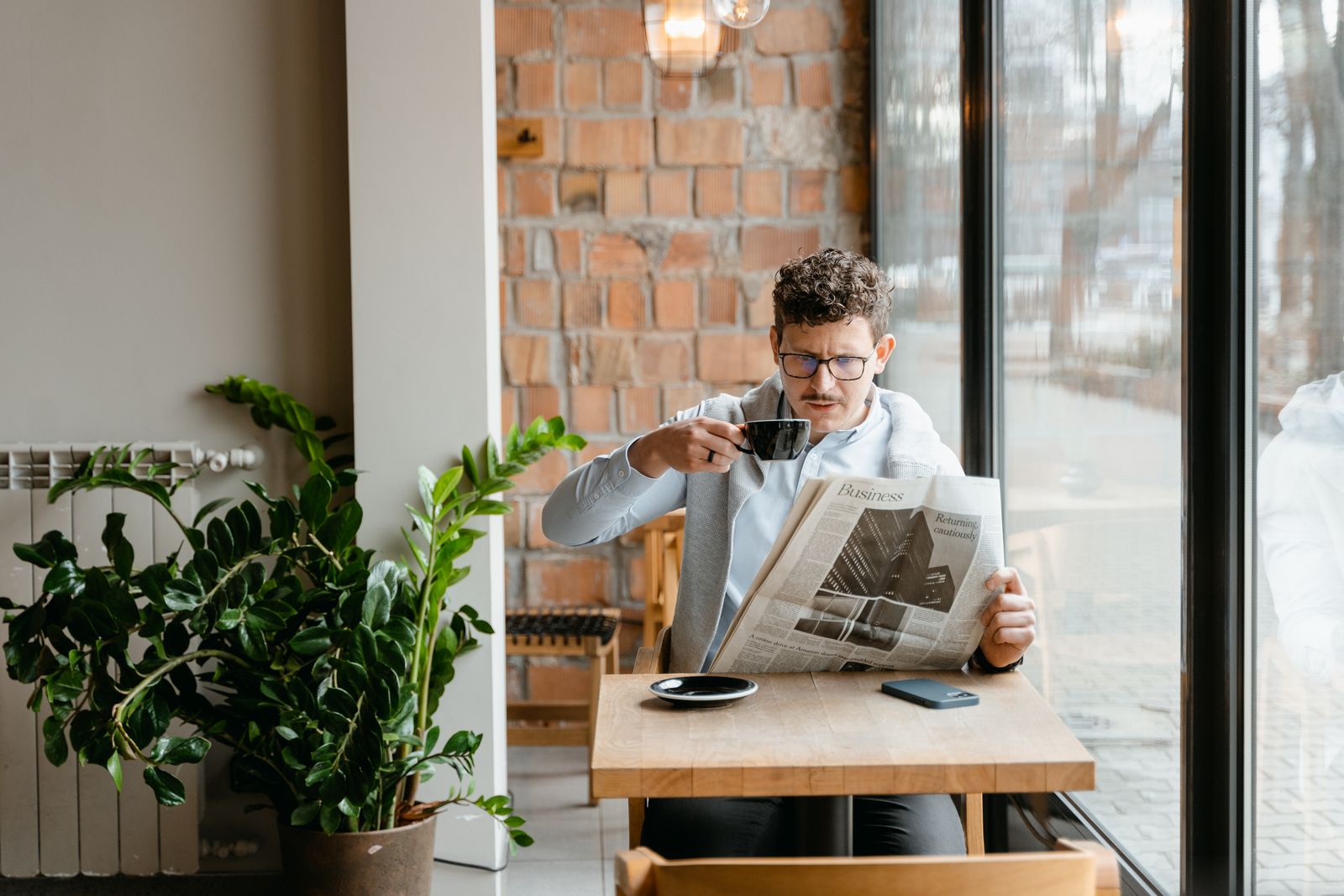 Man läser en tidning med kaffe på ett kafé