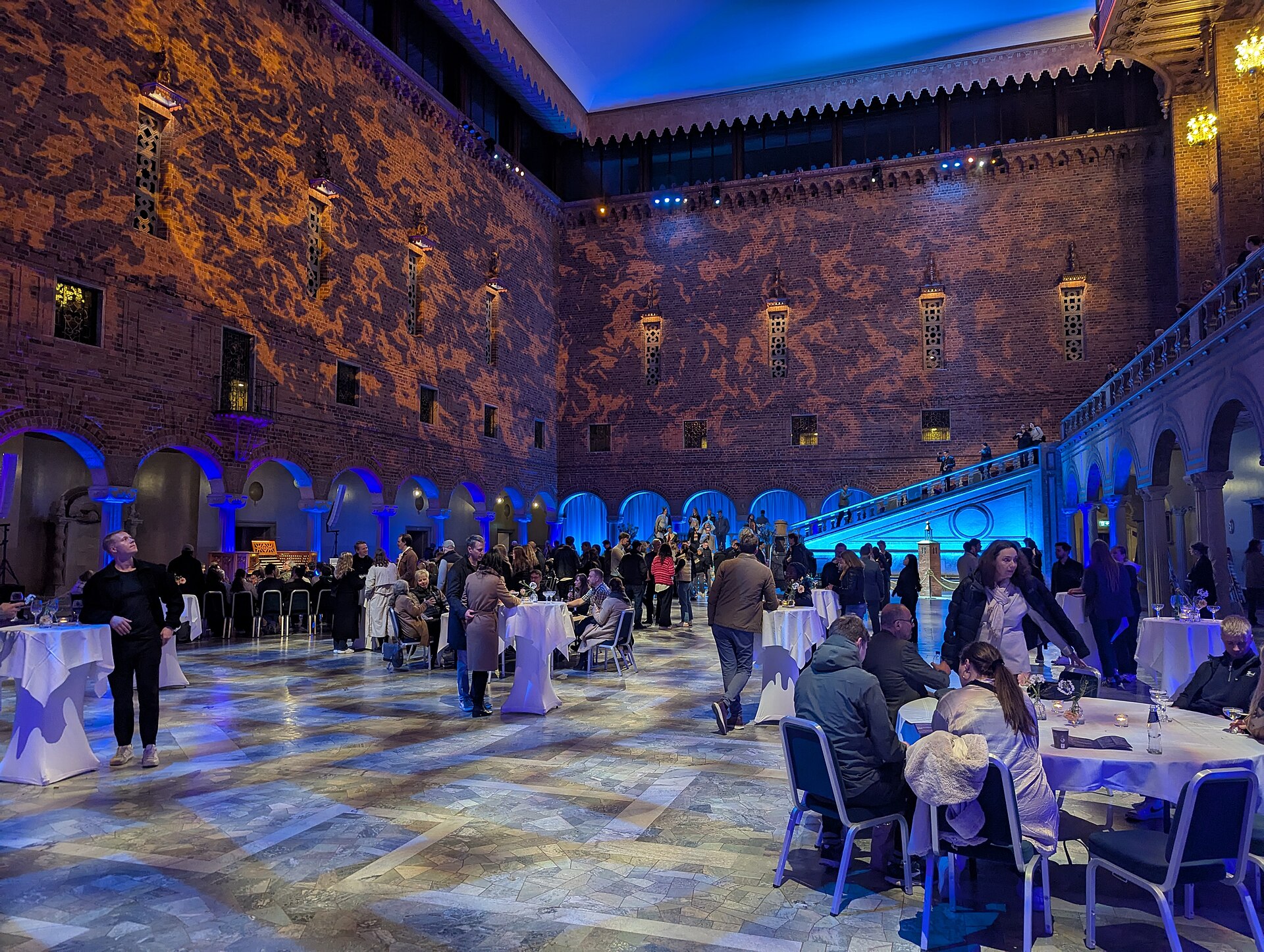 Besökare i Blå hallen i Stockholms stadshus under Kulturnatten, med upplysta tegelväggar och bord med vita dukar