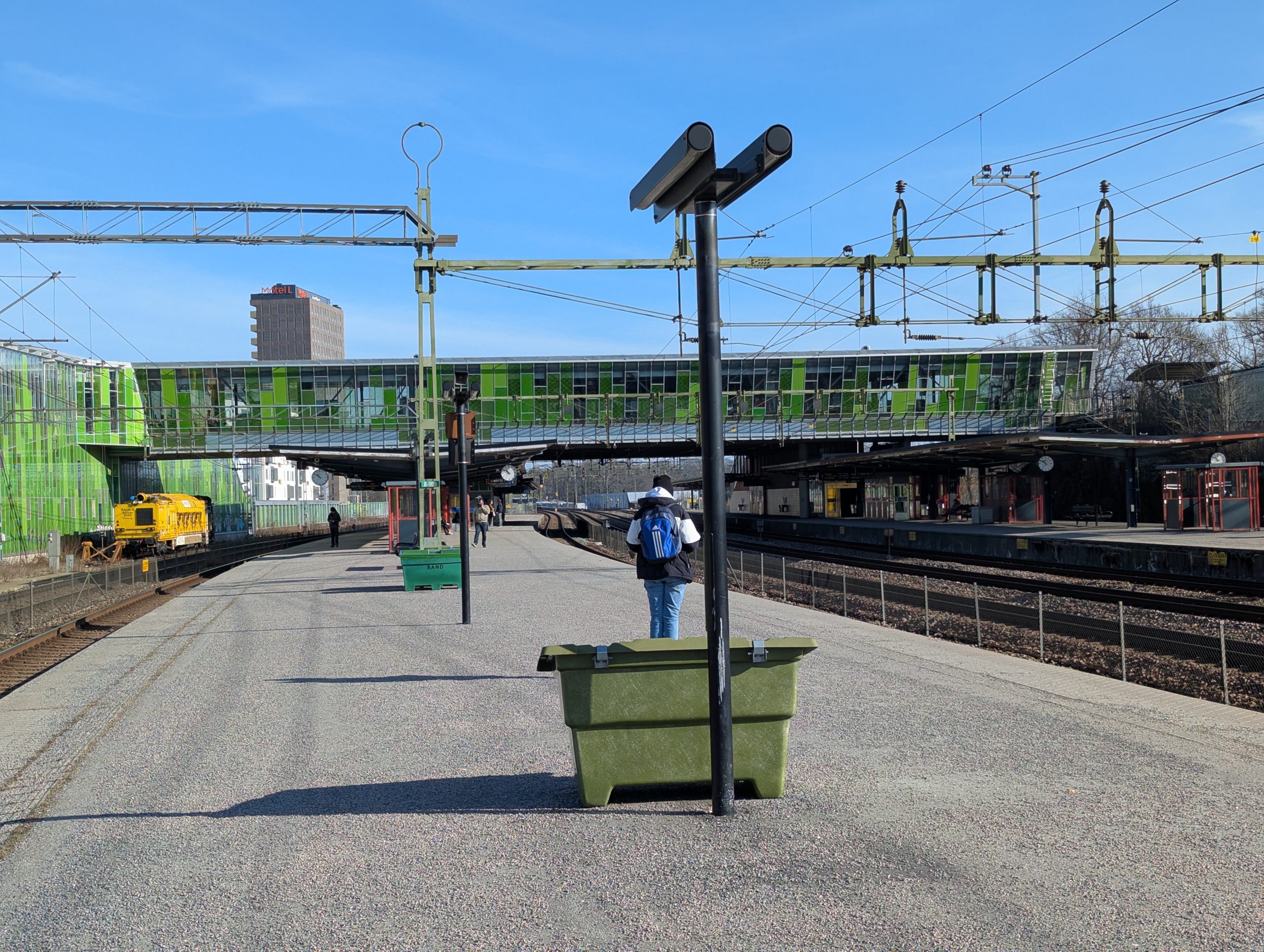 Perrongen vid Älvsjö station med den gröna gångbron över spåren