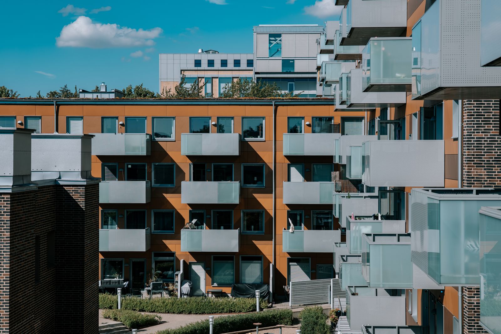 Flerbostadshus i ett bostadsområde med balkonger och grönska på gården