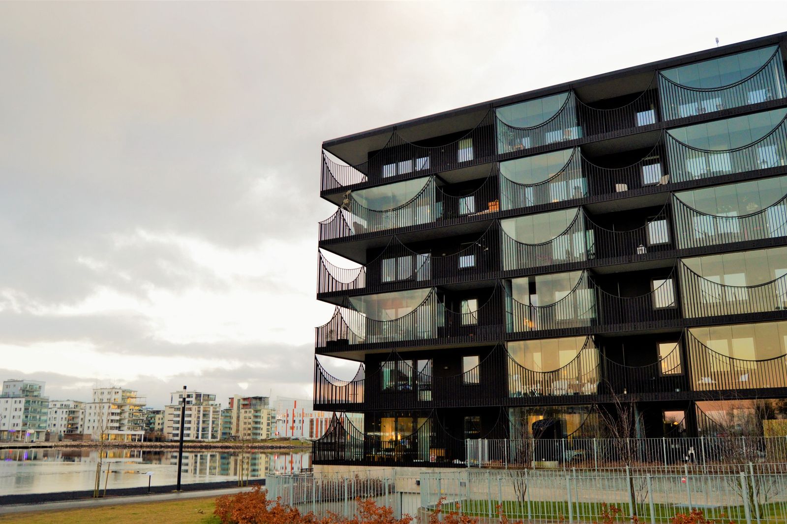 Modernt flerbostadshus vid vattnet med kringliggande bostadskvarter