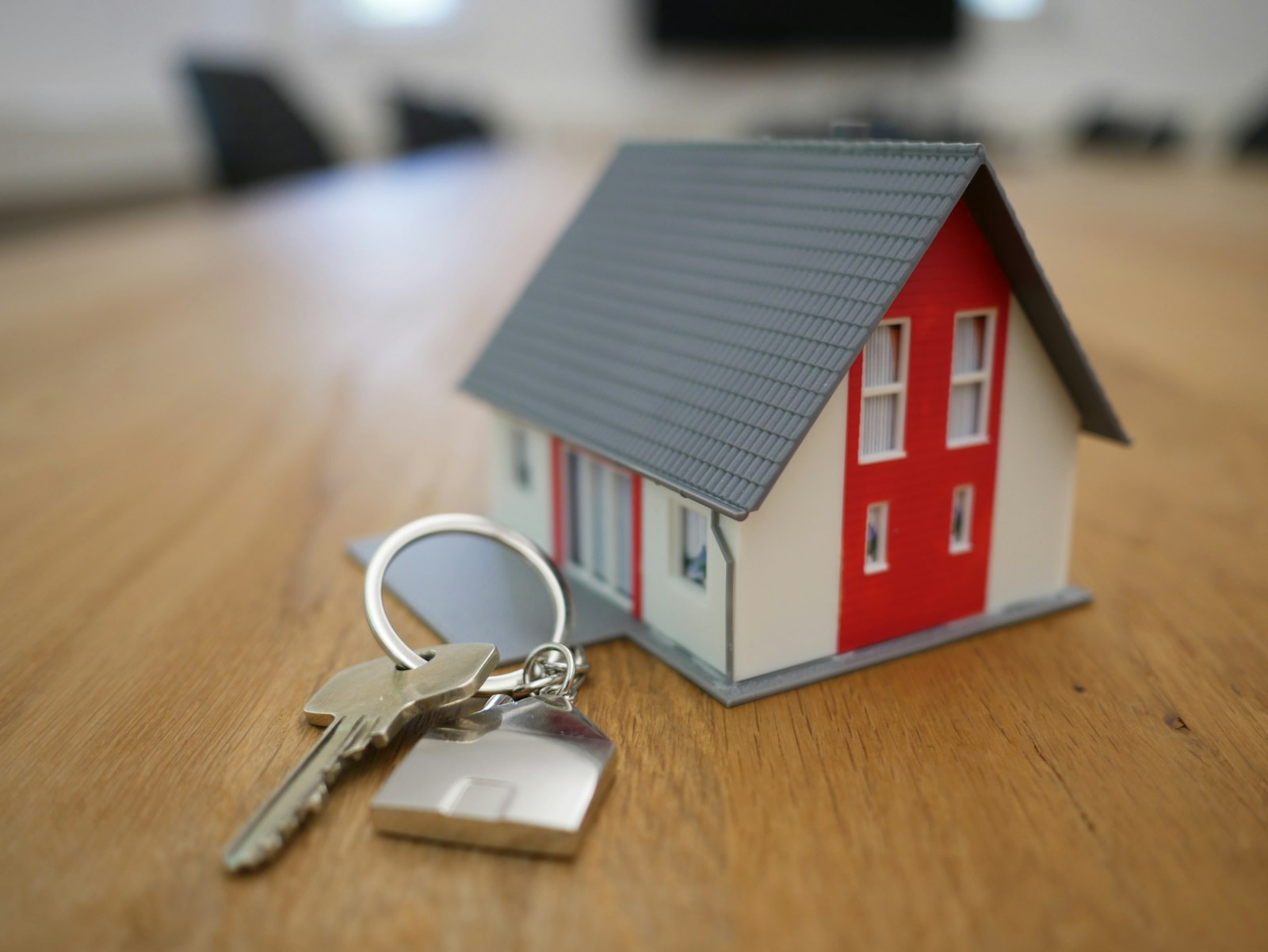 Modell av rött hus med grått tak bredvid en nyckelknippa