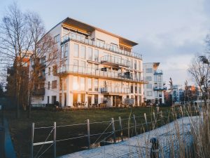 Vitt flerbostadshus med balkonger i kvällssol vid en brygga