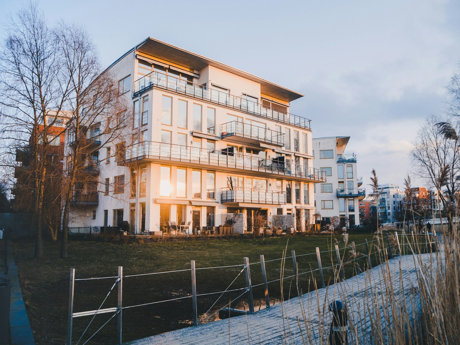 Vitt flerbostadshus med balkonger i kvällssol vid en brygga