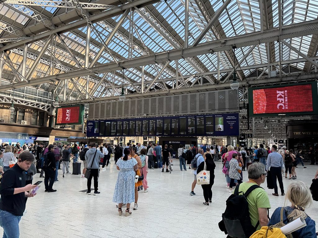Resenärer i den glastäckta biljetthallen på Glasgow Central station