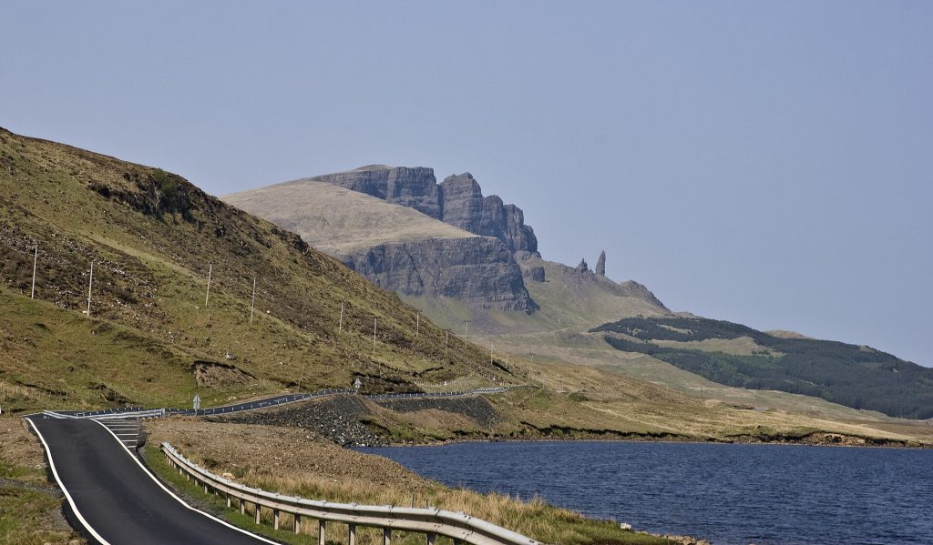 Vägen A855 slingrar sig längs Loch Leathan med Storrs klippvägg och Old Man of Storr på horisonten
