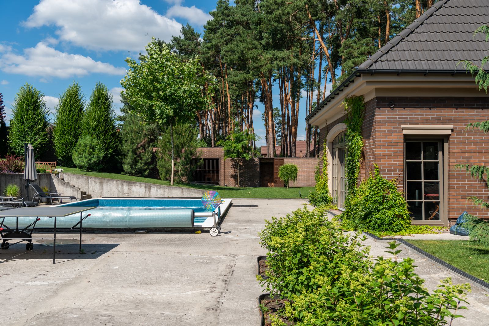 Utomhuspool i trädgård med pooltäcke delvis pårullat