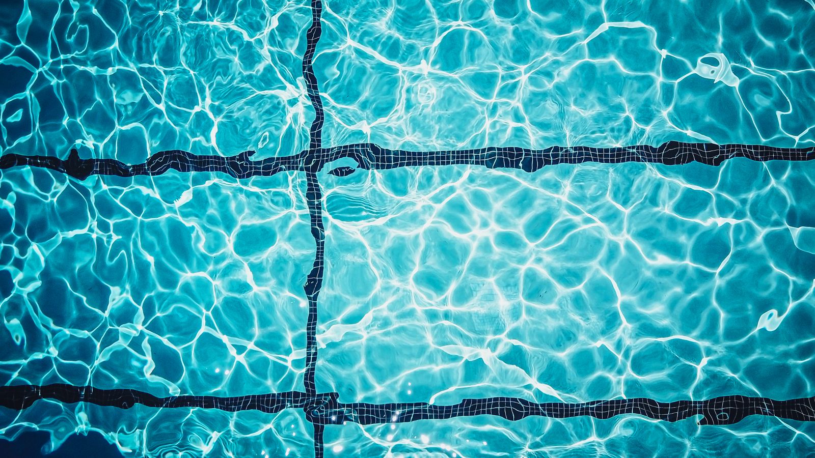 Klart turkost poolvatten med kakelfogar