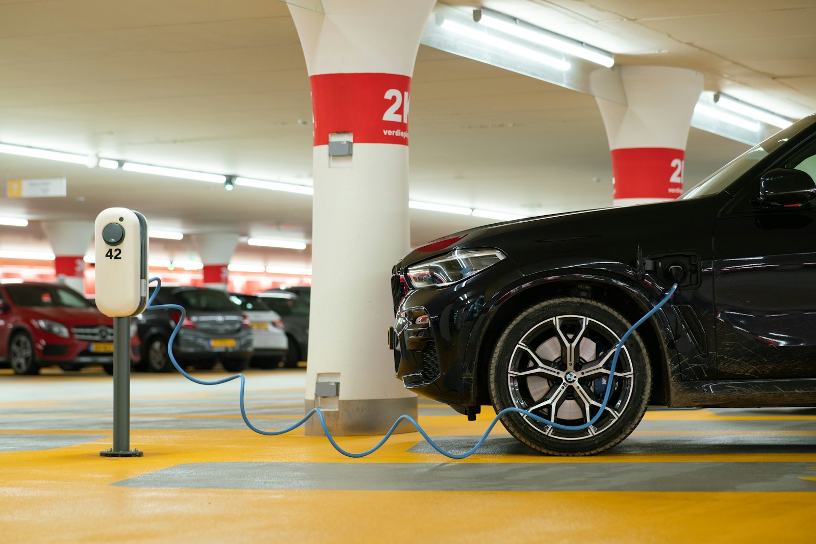 Elbil ansluten till laddstolpe i ett parkeringsgarage under ett flerbostadshus