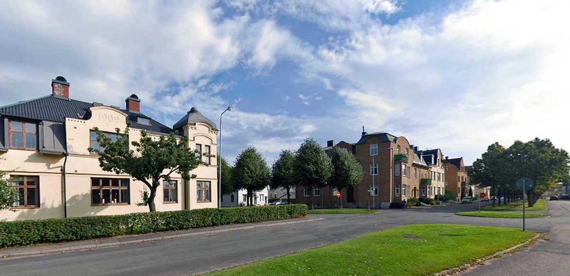 Flerbostadshus i tegel och puts längs en trädkantad gata på Västermalm i Skövde